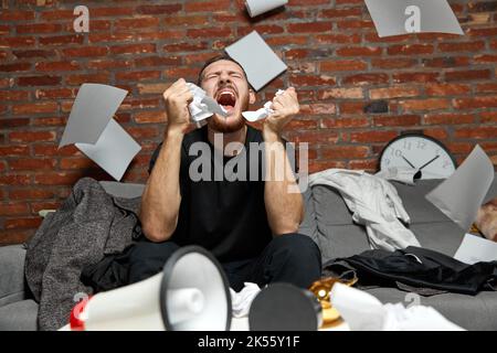 Stressed businessman or programmer working at home or office with anxiety checking time on clock, being in delay, deadline. Concentrated male Stock Photo