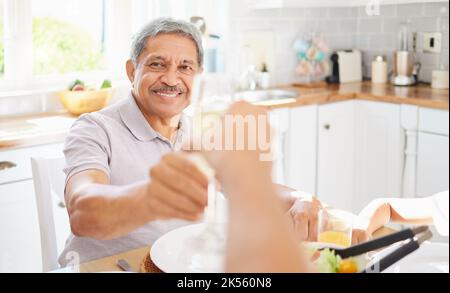 Champagne, glass and senior couple man for birthday celebration in Mexico home kitchen. Happy elderly people celebrate holiday with alcohol wine Stock Photo