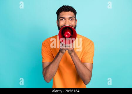 Photo of funky funny man dressed orange t-shirt making announcement loudspeaker isolated turquoise color background Stock Photo