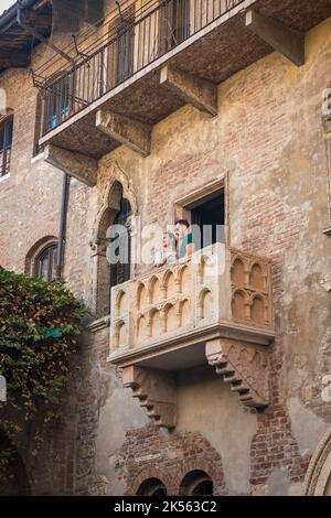 Verona balcony, view of a young couple standing on the balcony of the Casa di Giulietta (Juliet's House) sited in the historic centre of Verona, Italy Stock Photo
