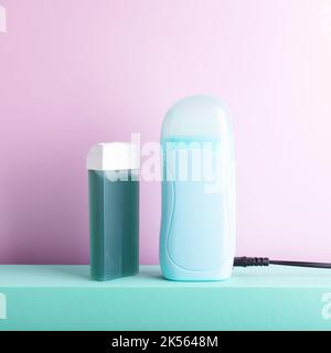 Front view of depilatory electric heater and hair removal wax cartridge standing on decorative podium against lilac background with some blank space. Stock Photo