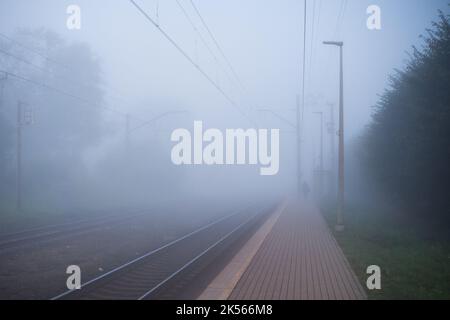 A lonely person in thick fog on a platform of the train station Stock Photo