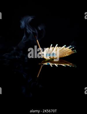 Some matches, one of which has just been extinguished with the smoke on it, are placed inside a scallop shell Stock Photo