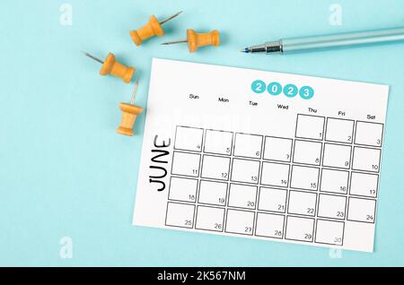 June 2023 Monthly calendar for 2023 year with pen on blue background.