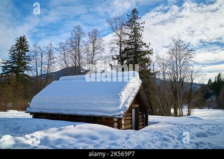 Rustic Log Cabin in Winter. A winter landscape with a rustic snow covered log cabin. Stock Photo