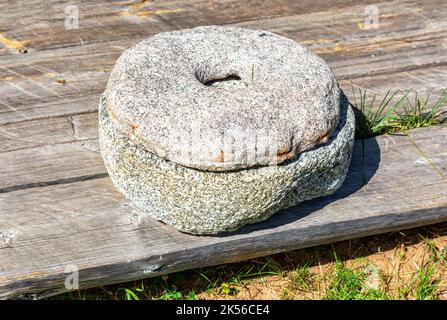 Ancient stone rotary mill for hand-grinding a grain into flour. Old hand-driven mill grinding wheat Stock Photo