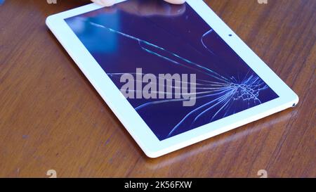 Tablet computer with a broken glass screen lying on the table. Stock Photo