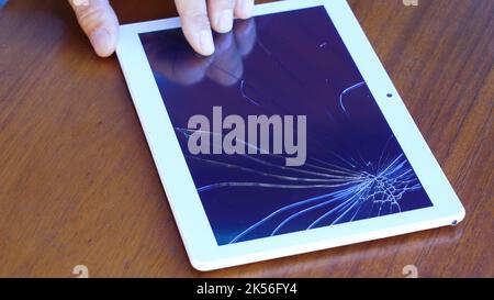 Tablet computer with a broken glass screen lying on the table. Stock Photo