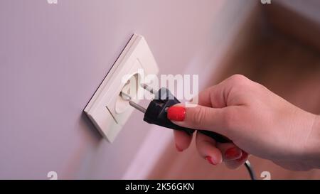 Hand inserts plug into socket closeup. Use of promising energy in home Stock Photo