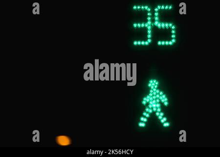 Pedestrian crossing traffic light shows green allow signal to go with seconds timer over black night background Stock Photo