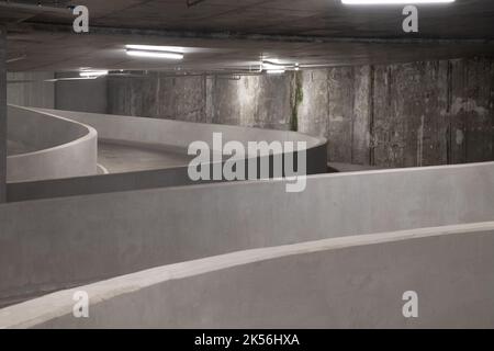 Perspective view of Curving shaped ramp of the basement made of concrete.  Curved down to the underground car parking garage,   Way down to undergroun Stock Photo