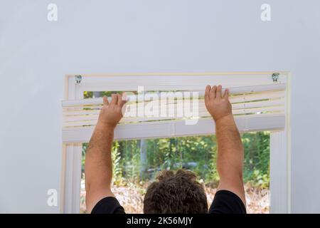 Contractor installation of window blinds to new home Stock Photo