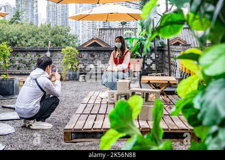 (221006) -- CHONGQING, Oct. 6, 2022 (Xinhua) -- A tourist poses for a photo in a commercial complex reconstructed from an old building in Yuzhong District, southwest China's Chongqing, Oct. 6, 2022.  In recent years, Chongqing has rebuilt and renovated a large number of idle and abandoned buildings in Yuzhong District.    The renewed buildings and neighborhoods have attracted many young entrepreneurs to start their business in catering, cultural and creative industries, and also helped promote tourism in Chongqing. (Xinhua/Tang Yi) Stock Photo