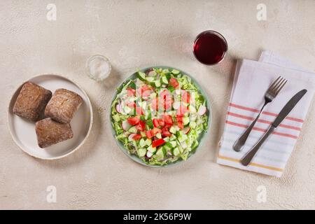 Full bowl of fresh green salad top view on a light table against a dark background on a rustic kitchen. Concept helpful and simple food Stock Photo