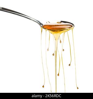 Honey dripping from spoon with droplets, isolated on white. Stock Photo