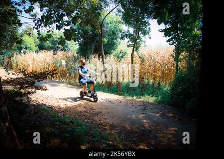 Man sitting and riding on a scooter in the park Stock Photo