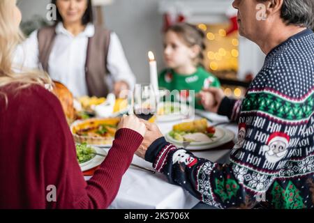 multiethnic family holding hands and praying near festive dinner during christmas celebration,stock image Stock Photo