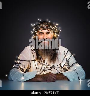 man with beard and long hair smiling with christmas lights Stock Photo