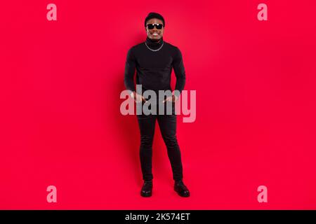 Full length body size view of attractive cheerful funky guy wearing black garment posing isolated over bright red color background Stock Photo