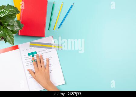 Child affected by dyslexia doing homework, reading book using colored rulers overlays strips. Top view to desk with books and school supplies Stock Photo