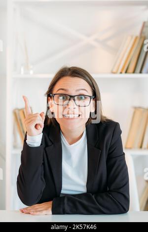 Business idea. Aha insight. Professional strategy. Inspired enthusiastic excited smart woman in eyeglasses pointing up at free space in light office i Stock Photo