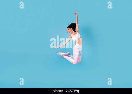 Full size photo of energetic japanese lady jump high enjoy weight loss wear trendy look for sports isolated on bright blue color background Stock Photo