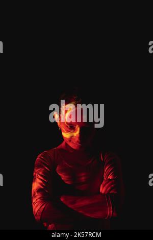 Children behavior. Kids discipline. Parenting problem. Hyperactive child. Evil smiling little girl in red yellow flame projector light isolated on bla Stock Photo