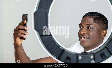 Morning selfie. Blogger black man. Hygiene grooming. Perfect face care. Everyday routine. Happy confident african guy admiring making photo mobile pho Stock Photo