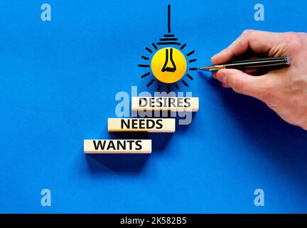 Wants needs and desires symbol. Concept words Wants Needs Desires on wooden blocks. Businessman hand. Beautiful blue background. Business, psychologic Stock Photo