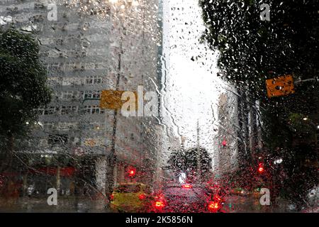 Rain drops on car window. Cold weather rainy season, cloudy wet day. Lonely mood. Town blurry background. Driver point of view. Stock Photo