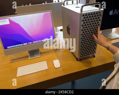Paris, France - Sep 9, 2022: Rear view of woman touching the ventilation holes of the Mac Pro workstation computer inside Apple Computers Store - looking at the Cinema XD display Stock Photo