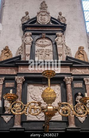 Germany, Lubeck - July 13, 2022: Marienkirche. Closeup of Johann Fuchting  Epitaph, white sculptures and black marble with golden chandelier against w Stock Photo