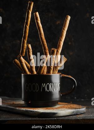 Holiday spirit, Christmas spirit. Fragrant cinnamon sticks in a black cup isolated on a black background. Spices, aromatic additives to coffee, tea, a Stock Photo