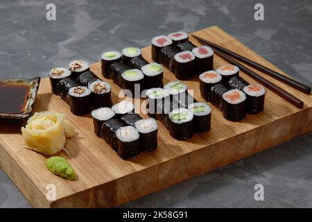 Different types of delicious and juicy sushi and rolls on a wooden board Stock Photo