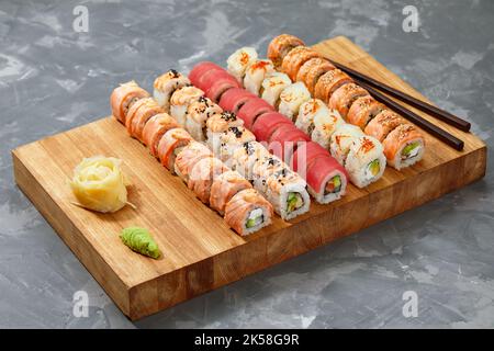 Different types of delicious and juicy sushi and rolls on a wooden board Stock Photo