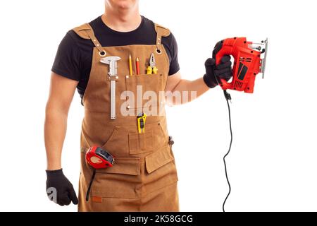 Carpenter in workers apron holding electric jig saw on white background Stock Photo