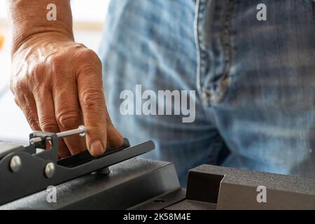 man installing the wall base for the television, it is a smart tv, adjusting with screwdriver Stock Photo