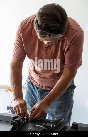 Mexican Latino man repairing a TV screen, checking for faults. Stock Photo