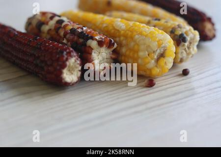 Multi colored indian corn made for Thanksgiving decoration.  Southwestern harvest corn on white wooden table. Light background. Side view. Close-up. C Stock Photo