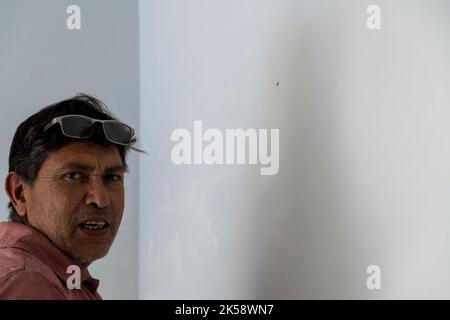 latin man repairing wall, white wall background, latin america Stock Photo