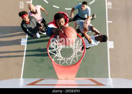 Overhead view of basketball player slam dunking ball in net