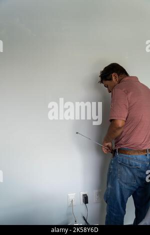 Senior man measure wall with measuring tape repairing apartment. Mature husband redecorate house Stock Photo