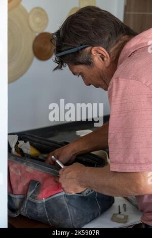 latino man looking for tools in his toolbox, hispanic, with screwdriver in hand Stock Photo