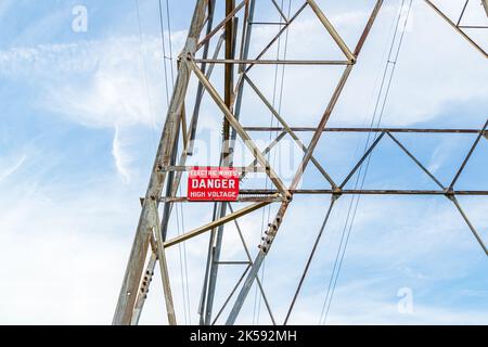 High voltage warning sign on electrical utility tower. Electricity, power lines, and electrical grid safety concept Stock Photo