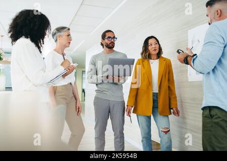 Group of diverse design professionals sharing ideas during a meeting in a modern office. Team of innovative businesspeople collaborating on a new crea Stock Photo