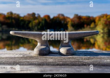 A cleat on dock waits for a boat to tie up on this small lake. Stock Photo