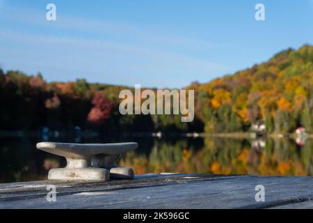 A cleat on dock waits for a boat to tie up on this small lake. Stock Photo