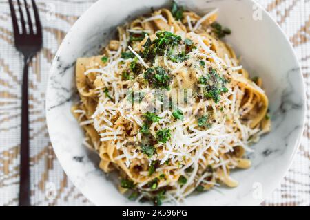 plant-based fettuccini pasta with creamy lemon and parsley sauce topped with fresh herbs and dairy-freee cheese, healthy vegan food recipes Stock Photo