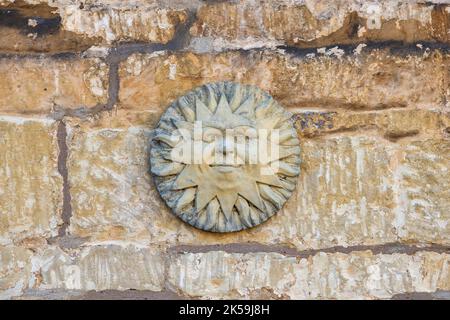 Stone sun on a cotswold stone house wall. Cotswolds, England Stock Photo
