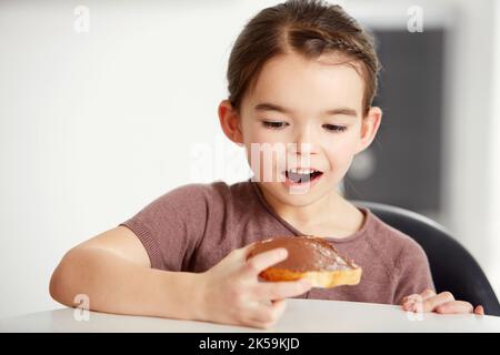 Ah yeah My favourite. a little girl looking excitedly at a piece of toast with chocolate spread on it. Stock Photo